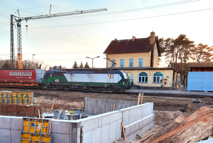Blick auf den Bahnhof in Zossen mit vorbeifahrendem Güterzug und Baustelle im Vordergrund
